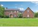 Traditional two-story brick home with a lush lawn and manicured landscaping in a peaceful neighborhood at 1121 N Cambridge Ct, Greenfield, IN 46140