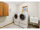 Well-lit laundry room featuring a washer and dryer set, utility sink, window, and cabinet at 1121 N Cambridge Ct, Greenfield, IN 46140