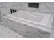 Close-up of a large soaking tub with marble tile surround and jet features at 1141 Temperance Ave, Indianapolis, IN 46203