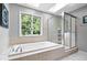 Bright bathroom features a soaking tub beneath a window and a glass-enclosed shower with tiled surround at 11956 Glen Cove Dr, Indianapolis, IN 46236