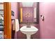 Cozy powder room with pedestal sink, decorative mirror, and unique purple walls at 11956 Glen Cove Dr, Indianapolis, IN 46236