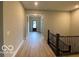 Hallway with hardwood floors lead to the front door with detailed dark railing at 12511 Lowery Way, Fishers, IN 46037