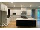 Bright, open kitchen with white cabinetry, stainless steel appliances, island with a dark base, and hardwood floors at 12511 Lowery Way, Fishers, IN 46037