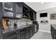 Stylish basement bar area with dark cabinets, wine storage, and a sleek backsplash, ideal for hosting guests at 12999 Deerstyne Green St, Carmel, IN 46032
