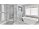 Elegant bathroom featuring marble walls, a freestanding tub, and a glass-enclosed shower at 12999 Deerstyne Green St, Carmel, IN 46032