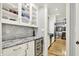 Charming butler's pantry with granite countertops, wine fridge, glass cabinets, and marble backsplash at 12999 Deerstyne Green St, Carmel, IN 46032