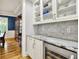 Close-up of a butler's pantry showcasing granite countertops, marble backsplash, glass cabinets, and wine fridge at 12999 Deerstyne Green St, Carmel, IN 46032