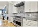 Gourmet kitchen with a professional gas range, marble backsplash, granite counters and white cabinets at 12999 Deerstyne Green St, Carmel, IN 46032
