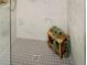 A modern shower features large, light gray tiles, a small stool, and a square drain at 1822 Central Ave, Indianapolis, IN 46202