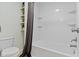 Bright bathroom features a tub with shower, white tile, and floating shelves for storage at 3014 Saddlehorn Dr, Carmel, IN 46033