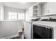 Bright laundry room features modern washer and dryer, white cabinets, and natural light from two windows at 4926 Crittenden Ave, Indianapolis, IN 46205