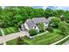 Stunning aerial view showcasing the home's manicured lawn, basketball court, and lush surrounding greenery at 5268 Woodfield Dr N, Carmel, IN 46033