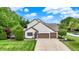 Beautiful home exterior featuring a well-maintained lawn, mature trees, and a long driveway at 5268 Woodfield Dr N, Carmel, IN 46033