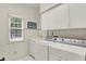 Bright laundry room with a window, washer, dryer, and ample storage cabinets at 5268 Woodfield Dr N, Carmel, IN 46033