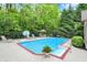 Inviting backyard pool area with lounge chairs, dining set, mature trees, and privacy fence at 5268 Woodfield Dr N, Carmel, IN 46033