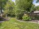 Beautifully landscaped backyard with lush green lawn, stone-lined flowerbeds, and mature trees at 5342 Central Ave, Indianapolis, IN 46220
