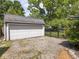A detached garage with gravel driveway and black metal fence surrounded by mature trees at 5342 Central Ave, Indianapolis, IN 46220