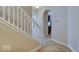 Inviting hallway with staircase, neutral walls, and an arched doorway leading to the kitchen at 5768 Blue Sky Dr, Whitestown, IN 46075