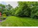 A lush green backyard is surrounded by mature trees and greenery at 6455 N Olney St, Indianapolis, IN 46220