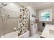 Classic bathroom with gray tile, a tub, and a shower with a patterned curtain beside a window at 6455 N Olney St, Indianapolis, IN 46220