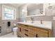 Bright bathroom featuring a wood vanity, dual sinks, and a window offering a view of outdoors at 6455 N Olney St, Indianapolis, IN 46220