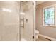 Contemporary bathroom with a walk-in shower featuring glass doors, and white tiling near a window at 6455 N Olney St, Indianapolis, IN 46220