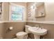 Bathroom featuring a pedestal sink, wainscoting, and a window providing natural light at 6455 N Olney St, Indianapolis, IN 46220