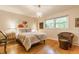 Cozy bedroom featuring wood floors, a chandelier, chair, and a comfortable bed near window at 6455 N Olney St, Indianapolis, IN 46220
