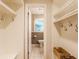 Well-organized mudroom with white shelving, coat hooks, and a view into a half bathroom with tiled floor at 6455 N Olney St, Indianapolis, IN 46220