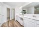 This primary bathroom has a double sink vanity, white cabinets, framed mirror, wood-look flooring, and a walk-in closet at 6841 Seabiscuit Rd, Whitestown, IN 46075