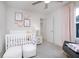 Bright Bedroom features pink accents, white crib, two plush ottomans and adjacent sitting area with rocking chair at 6841 Seabiscuit Rd, Whitestown, IN 46075