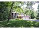 Inviting brick home with a two-car garage nestled amongst mature trees and a green lawn at 7115 Fremont Ct, Indianapolis, IN 46256