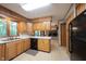 Functional kitchen with wood cabinetry, laminate countertops, and black appliances at 7115 Fremont Ct, Indianapolis, IN 46256