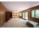Open living room with wood-paneled walls, fireplace, and view into adjacent kitchen at 7115 Fremont Ct, Indianapolis, IN 46256