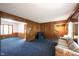 Spacious living room showcasing classic wood paneling, blue carpeting, and an open layout leading to adjacent rooms at 7115 Fremont Ct, Indianapolis, IN 46256