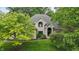 Light brick home with a manicured lawn, mature trees, and arched entryway, providing timeless appeal and elegance at 7138 Nile Ridge Ct, Indianapolis, IN 46236
