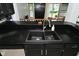 Close-up of a modern kitchen sink with black countertops, stainless steel dishwasher, and dark cabinets at 7529 Oceanline Dr, Indianapolis, IN 46214