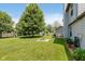 Expansive backyard featuring a large tree, fire pit, patio set, swing set, and lush lawn at 7742 Bayridge Dr, Indianapolis, IN 46236