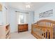 Light and airy bedroom with light blue walls, wood crib, dresser and inspirational saying on the wall at 7742 Bayridge Dr, Indianapolis, IN 46236