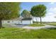 Backyard view of a ranch home and garage, surrounded by trees and gravel driveway at 8370 State Road 236, North Salem, IN 46165