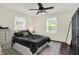 Comfortable bedroom with ceiling fan, two windows for natural light, and a dark-wood accent wall at 907 N Arlington Ave, Indianapolis, IN 46219