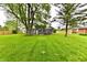 Spacious backyard featuring lush green grass, mature trees, and a well-maintained fence for privacy and security at 9080 W Forest Dr, Elwood, IN 46036