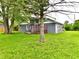 Backyard view of this single-Gathering home showing mature trees and a grassy lawn at 9080 W Forest Dr, Elwood, IN 46036