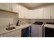 Bright laundry room featuring white cabinets, modern appliances, countertop space, and a sink at 9640 Katana Cir, Fishers, IN 46040