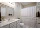 Bright bathroom featuring white marble floors, vanity with sink, toilet, and a shower with curtain at 9743 Herons Cv, Carmel, IN 46280