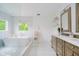 Bright bathroom featuring a soaking tub below a window, double vanity, and a separate water closet at 10243 Brixton Ln, Fishers, IN 46037