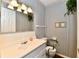 Functional bathroom with a single vanity, mirror, and toilet, featuring blue striped wallpaper, designed for everyday use at 1102 Fox Hill Dr, Indianapolis, IN 46228
