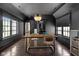 Dark painted dining room with wood floors features a modern light fixture, windows, and assorted seating at 11101 Hawthorn Rdg, Fishers, IN 46037