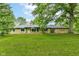 Sprawling brick ranch-style home features a large lawn, mature trees, and an American flag displayed in the front window at 1248 Hathaway Dr, Indianapolis, IN 46229