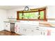 Bright kitchen with white cabinets and large window over a farmhouse sink with stainless steel dishwasher to the left at 1248 Hathaway Dr, Indianapolis, IN 46229